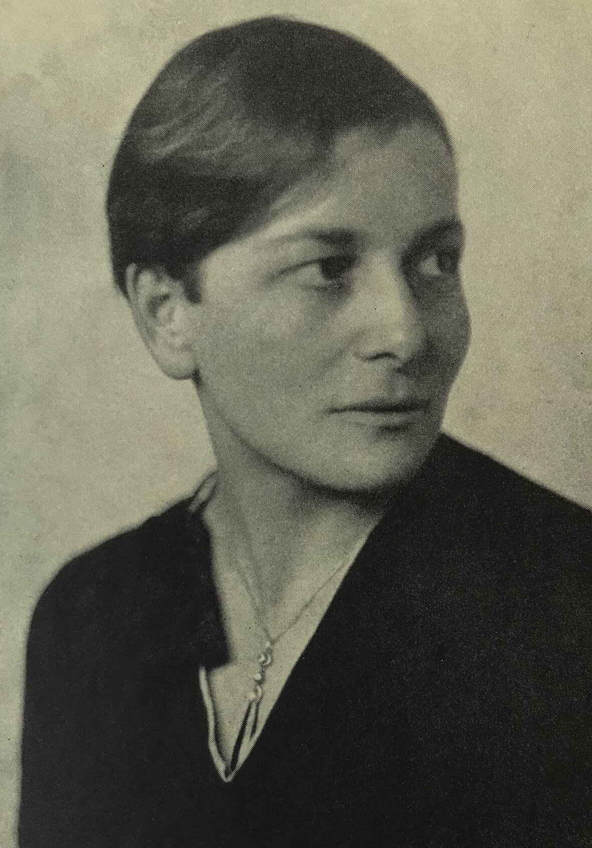 Ein schwarz weiß Portrait von Eva Ehrenberg. Sie schaut rechts an der Kamera vorbei, man sieht vor allem den Oberkörper und den Kopf, sie hat kurze Haare und trägt ein Hemd.